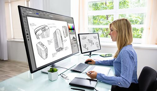 Woman at desk using design software on mulitple displays